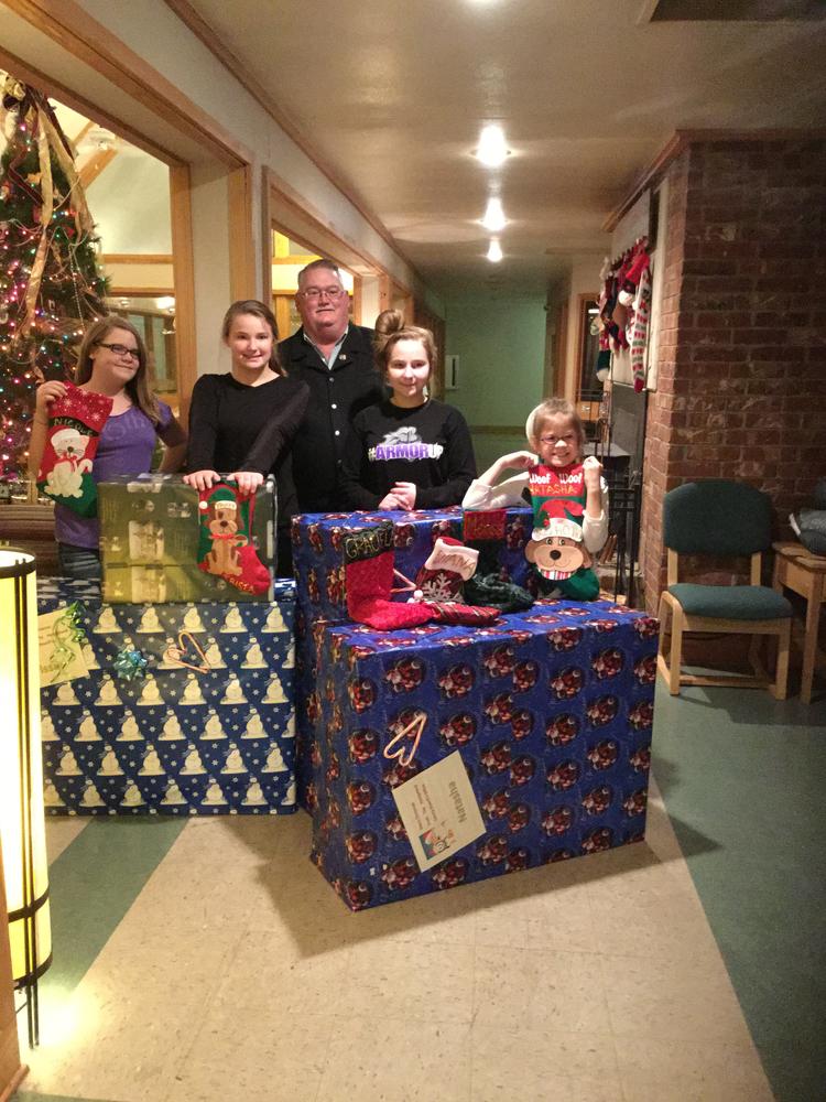 Four children and Sheriff stand behind large christmas presents