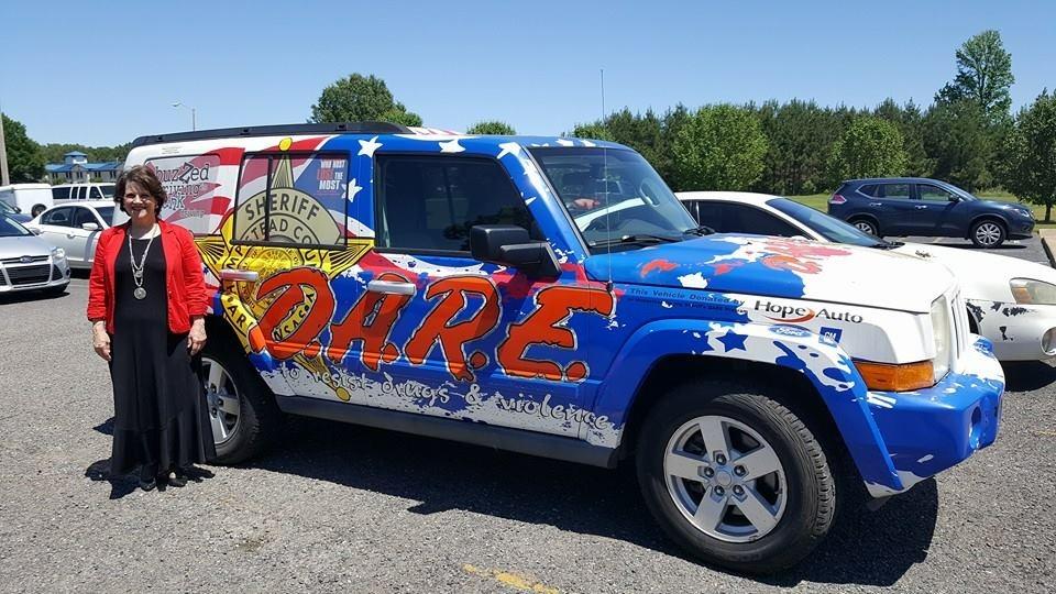 Teacher standing with DARE vehicle