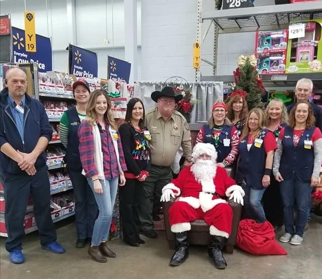 Sheriff's office staff and walmart staff standing with Santa Claus